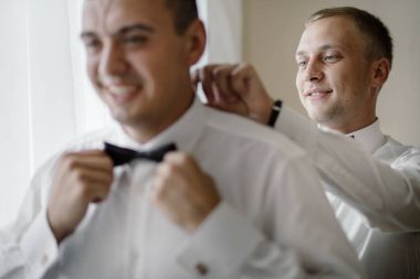 şık sağdıç mutlu yardımcı Damat Düğün töreni için sabah hazırlanıyor. Lüks Oda takım elbiseli bir adam. metin için yer. düğün günü.