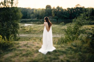 Doğa üzerinde poz uzun beyaz elbiseli genç kadın