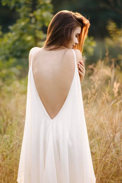 Young woman in long white dress posing on nature