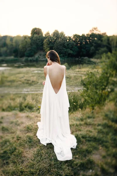 自然にポーズをとって長い白いドレスの若い女性 — ストック写真