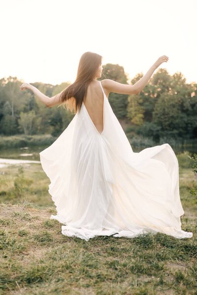 Young woman in long white dress posing on nature