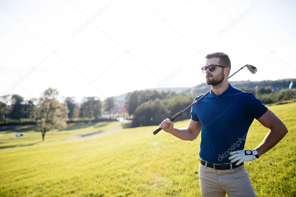 golf player hitting shot with club on course at beautiful morning with sun flare in background