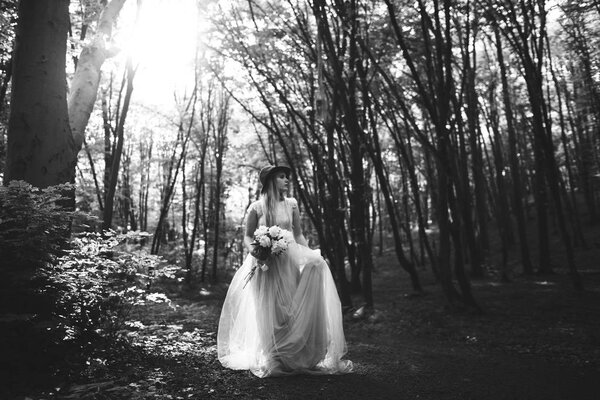 Beautiful young woman in a long dress posing in forest