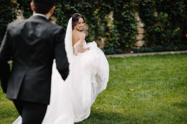 Şık gelin ve buket çiçek ile yaz yeşil parkta yürüyüş, dans ve having fun damat gülümseyen mutlu onların düğün günü