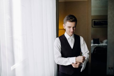 şık damat portre gecenin düğün için hazırlanıyor süre pencerenin.