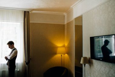 şık damat portre gecenin düğün için hazırlanıyor süre pencerenin.