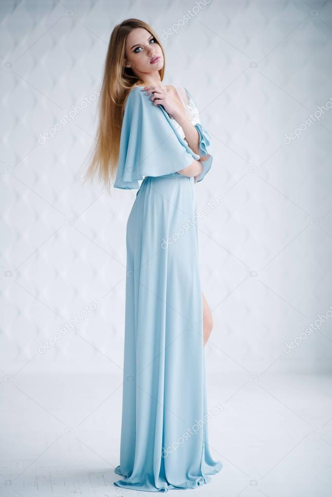 Beautiful young woman with make up  in blue dress posing in studio