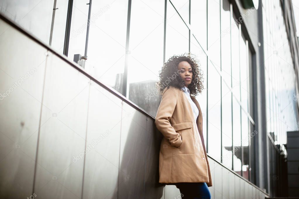 beautiful  African American woman in stylish coat  posing in city
