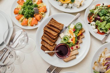 Yemekler masaya tatil için servis. Çatal bıçak takımı ve yemek restoranda beyaz masa örtüsü. Şenlikli bir ziyafet tasarlayın. Konuklar ve ziyaretçiler için lüks gıda.
