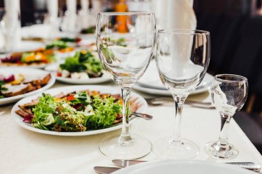 Yemekler masaya tatil için servis. Çatal bıçak takımı ve yemek restoranda beyaz masa örtüsü. Şenlikli bir ziyafet tasarlayın. Konuklar ve ziyaretçiler için lüks gıda.