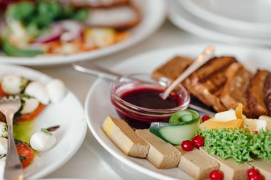 Yemekler masaya tatil için servis. Çatal bıçak takımı ve yemek restoranda beyaz masa örtüsü. Şenlikli bir ziyafet tasarlayın. Konuklar ve ziyaretçiler için lüks gıda.