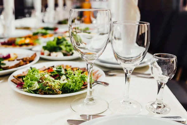 Yemekler masaya tatil için servis. Çatal bıçak takımı ve yemek restoranda beyaz masa örtüsü. Şenlikli bir ziyafet tasarlayın. Konuklar ve ziyaretçiler için lüks gıda.