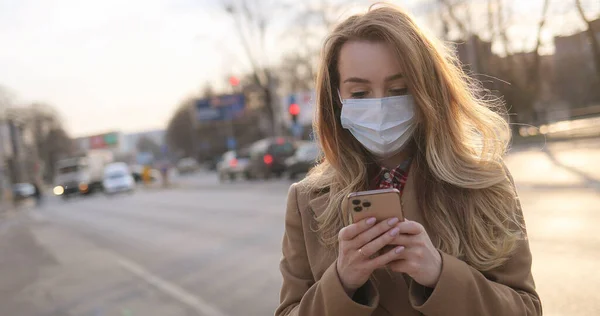 의료용 마스크 메시지를 휴대폰으로 도청하는 백인젊은 밖에서 스마트폰으로 타이핑하고 스크롤하는 — 스톡 사진