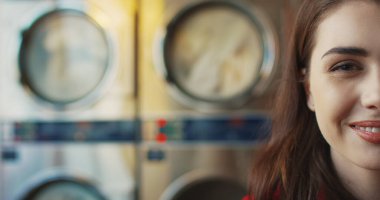 Kırmızı dudaklı, sarı gözlüklü ve çamaşırhanede kameraya gülümseyen beyaz, genç, şık bir kadının yüzünün yarısını kapatın..