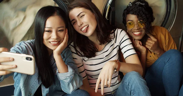 Három elég vegyes fajú barátságos lány mosógépben mosolygós okostelefon kamera, selfie fotó. — Stock Fotó