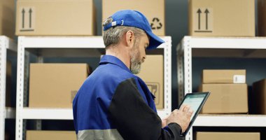 Mavi üniformalı ve şapkalı teslimatçının posta kutusundan geçerken arkadan görünüşü, sonra dönüp tablet cihazına tıklaması..