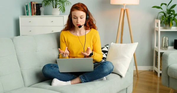 Portret van een mooi vrolijk roodharig meisje met headsets met laptop. Gelukkig vrouwtje heeft videogesprek. Concept afstandsonderwijs — Stockfoto