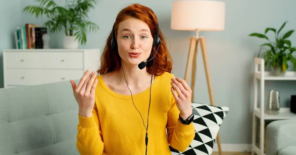 Retrato de bela menina ruiva alegre com fones de ouvido tem chamada de vídeo . — Fotografia de Stock