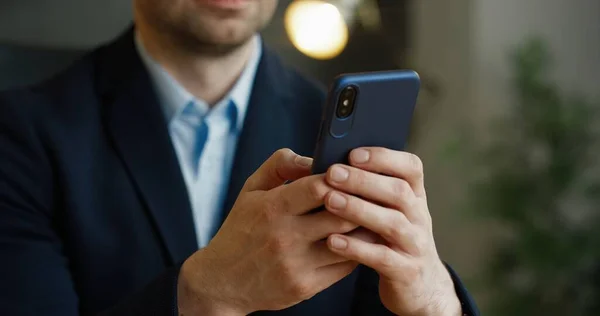 Sluiten van smartphone in handen. Zakenman afluisteren en scrollen op mobiele telefoon in kantoor. — Stockfoto