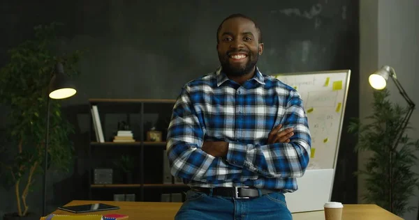 アフリカ系アメリカ人の陽気なハンサムな男の肖像画モトリーシャツオフィスの部屋に立って、カメラに喜んで笑みを浮かべて. — ストック写真
