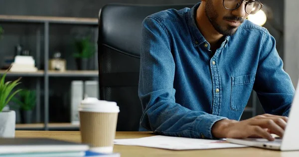 Close up of handsome young Arab busy male office worker sitting at table and working on laptop computer. — Stock Photo, Image