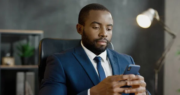 Snygg man knacka och rulla på mobiltelefon på kontoret. — Stockfoto