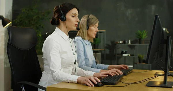 Kundenbetreuerin in drahtlosem Headset sitzt am Computerbildschirm und löst Problem des Kunden. — Stockfoto