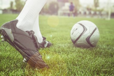cropped shot of feet with soccer ball on green grass