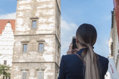 Kadın turist Prag'da güneş ve mavi gökyüzü altında çekim güneşli bir günde elinde onu telefon kamera ile. Prag'da popüler turistik yerlerinden