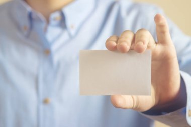 Beton duvar arka plan üzerinde beyaz kartvizit tutan adam