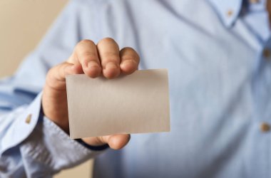 Beton duvar arka plan üzerinde beyaz kartvizit tutan adam