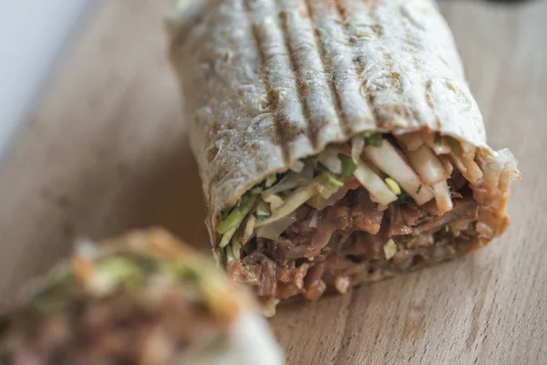 close-up shot of delicious doner wrap on wooden board