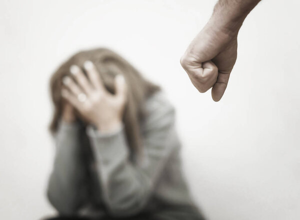 Мужчина избивает свою жену, иллюстрируя насилие в семье
