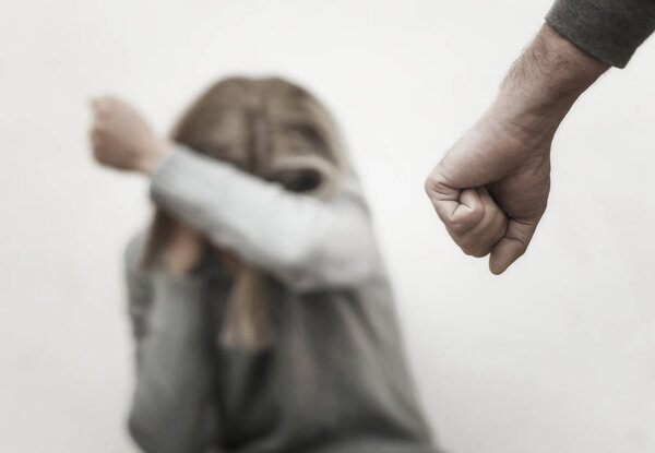 Мужчина избивает свою жену, иллюстрируя насилие в семье
