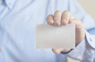 Beton duvar arka plan üzerinde beyaz kartvizit tutan adam