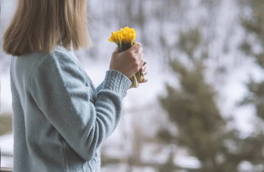 Elinde sarı bir buket bahar çiçeği olan bir kadın. 