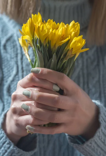 Kobieta z żółtym bukietem wiosennych kwiatów w rękach na — Zdjęcie stockowe