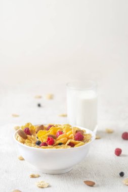 Beyaz arka planda ahududu ve yaban mersinli mısır gevreği. Kahvaltı. Böğürtlenli ve sütlü mısır gevreği. Mısır gevreği. Taze sağlıklı yiyecekler. Sabah yemeği. Tahta masa. Organik. Diyet kavramı.