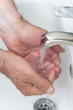 yaşlı adam banyoda ellerini yıkıyor