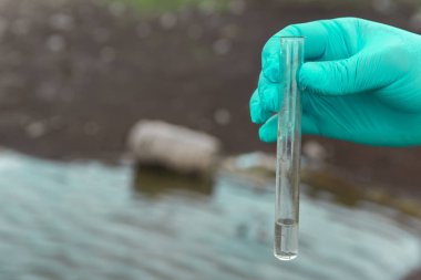Analiz için nehirden örnek su. Bir test tüpü tutan eldiven. Ekoloji konsepti.