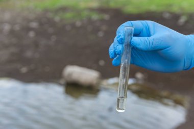 Nehirden bir su örneği. Eldiven takıp test tüpünde su topluyor. ekoloji kavramı