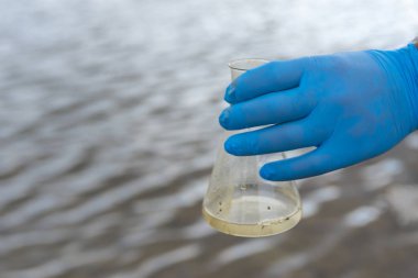 Analiz için nehirden örnek su. Bir test tüpü tutan eldiven. Ekoloji konsepti.