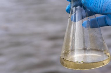 Nehirden bir su örneği. Eldiven takıp test tüpünde su topluyor. ekoloji kavramı