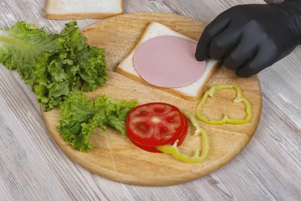 Man Black Gloves Prepare Sandwich Wooden Desk — Stock Photo, Image