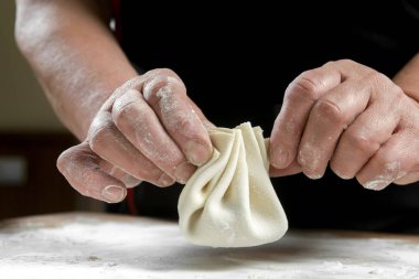 Aşçı ahşap masada khinkali yapıyor. İşlem hazırlığı Gürcistan yemeği. yiyecek konsepti.