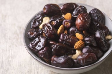 Beyaz ahşap arka planda fındık ve hurma karışımı sağlıklı yiyecekler.