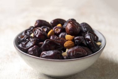 Beyaz ahşap arka planda fındık ve hurma karışımı sağlıklı yiyecekler.