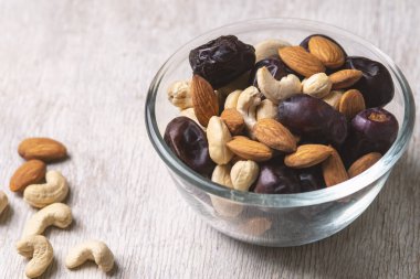 Beyaz ahşap arka planda fındık ve hurma karışımı sağlıklı yiyecekler.