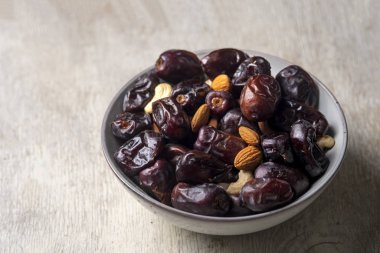 Beyaz ahşap arka planda fındık ve hurma karışımı sağlıklı yiyecekler.