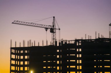 Endüstriyel makine ve inşaat vinç. Vinçler ve gökdelen yapım aşamasında, şehir manzarası, günbatımı, gündoğumu bina inşaat alanı altında.